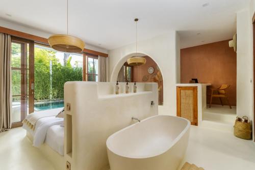 a large bathroom with a tub and a bed at White Goose Boutique Hotel in Canggu