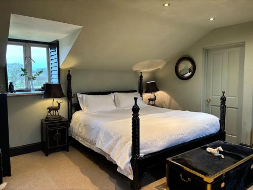 um quarto com uma cama grande com um cão deitado sobre ela em Stylish Secluded Country Retreat with Garden em Whitley