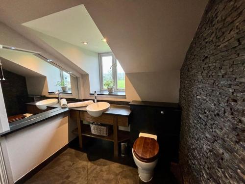 ein Badezimmer mit 2 Waschbecken und einer Steinmauer in der Unterkunft Stylish Secluded Country Retreat with Garden in Whitley