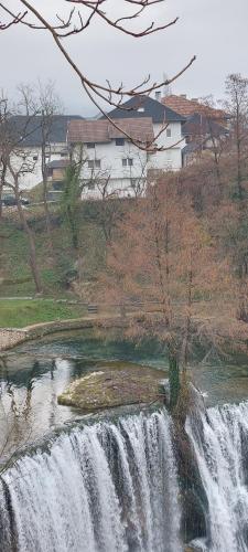 a waterfall in a field with a house in the background at Apartman Heli Meli 1 in Jajce