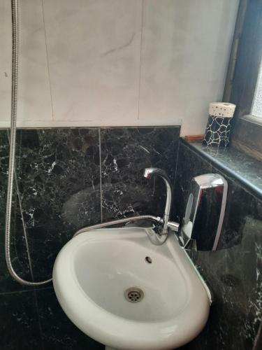 ein weißes Waschbecken im Bad mit schwarzen Fliesen in der Unterkunft D&D apartaments in Tbilisi City