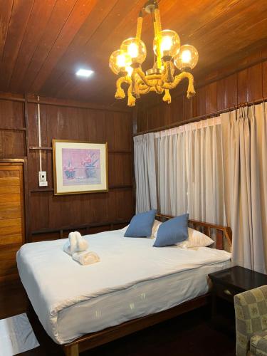 a bedroom with a large bed with a chandelier at บ้านสวนแก้วคำแพง Baan Suan Kaew Khampaeng in Udon Thani