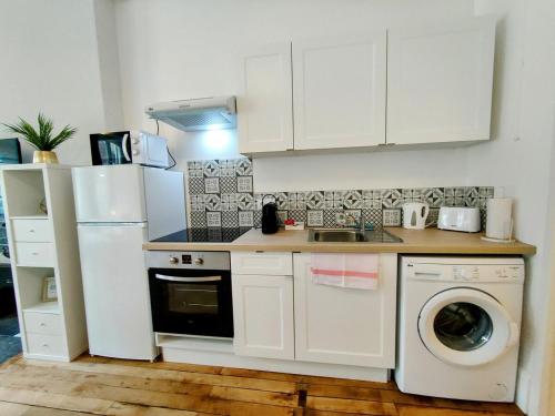 La cuisine est équipée d'un réfrigérateur blanc et d'un lave-vaisselle. dans l'établissement Paris IV - Séjour à Auxerre, à Auxerre