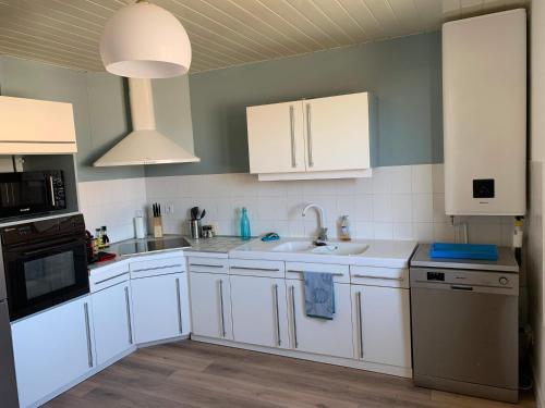 een keuken met witte kasten en een wastafel bij St Loup in Bessan