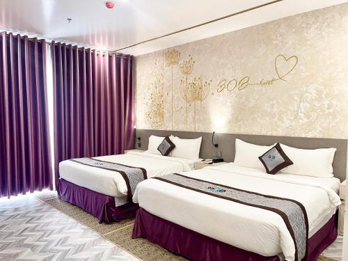 two beds in a hotel room with purple curtains at B.O.B Hotel in Cao Lãnh