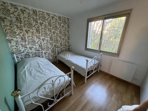 une chambre avec deux lits et une fenêtre dans l'établissement Appartement T2 au bord de mer avec parking, terrasse et piscine, à Sainte-Maxime