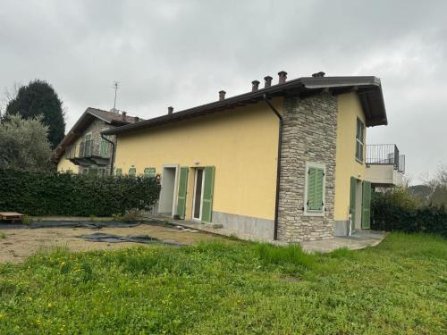 une maison jaune avec des portes vertes et une cour dans l'établissement Park 20 Guest House, à Azzate