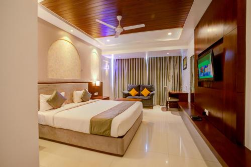 a bedroom with a bed and a tv and a couch at KAMAT'S DAFFODIL RESORT GOA in Pilerne