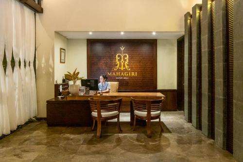 a woman sitting at a table in a restaurant at Mahagiri Villas Sanur in Sanur