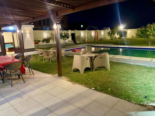 a patio with tables and chairs next to a swimming pool at night at شاليه للايجار اليومي بالريف الاوروبي in Qaryat ash Shamālī