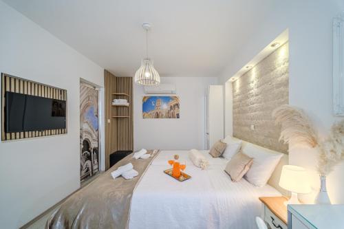 Central Split rooms and apartments Paese في سبليت: غرفة نوم بسرير ابيض كبير عليها لعبة