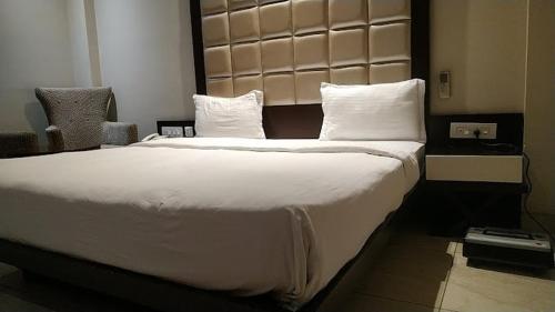 a bedroom with a large bed with white sheets and pillows at Hotel Samrat Heavens Meerut in Meerut