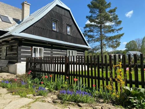 a fence in front of a house with flowers at Roubenka Kuklík in Sněžné