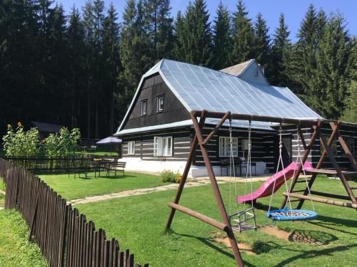 a house with a solar roof and a swing at Roubenka Kuklík in Sněžné