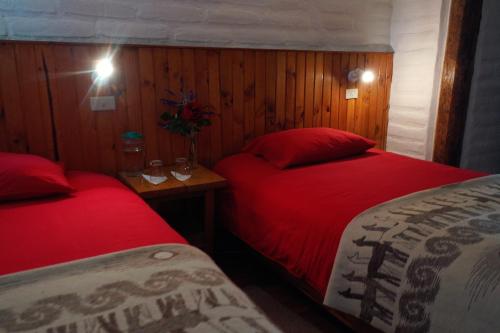 - 2 lits dans une petite chambre avec des draps rouges dans l'établissement Hostería Hotel Cuello de Luna - Cotopaxi - Country Inn, à Lasso