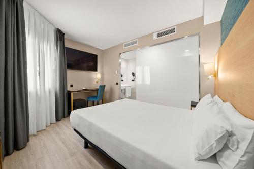 a hotel room with a bed and a desk at Hotel Zentral Ramiro I Oviedo in Oviedo