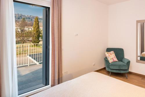 een slaapkamer met een bed, een stoel en een raam bij Panoramic Apartment Rudi in Garda