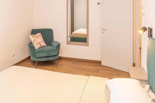 a bedroom with a green chair and a mirror at Panoramic Apartment Rudi in Garda