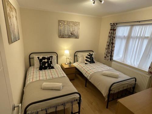 2 camas en una habitación pequeña con ventana en Spacious one bedroom apartment with free parking en Enfield