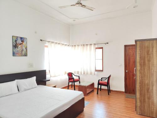 1 Schlafzimmer mit einem Bett, 2 Stühlen und einem Fenster in der Unterkunft Airport Forest View Ghugugti Farmstay in Dehradun