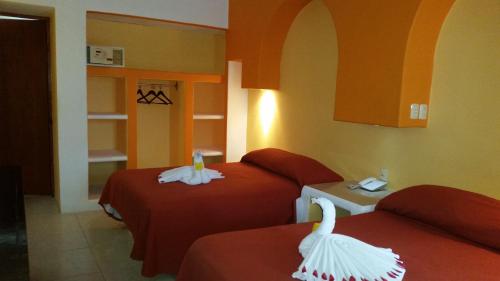 サンタ・クルス・ウアトゥルコにあるHotel Alikarのベッド2台(赤いシーツ、白いタオル付)が備わる客室です。