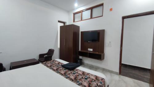 Habitación con cama, TV y silla. en Hotel triple s, en Karnal