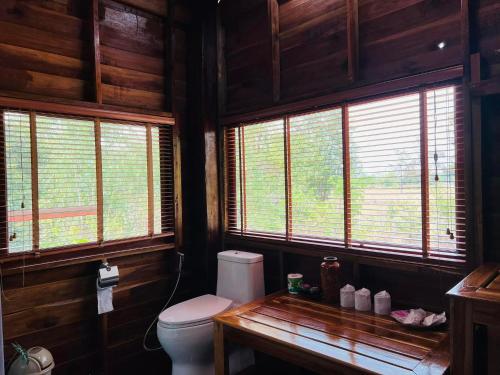 a bathroom with a toilet in a wooden cabin at บ้านสวนแก้วคำแพง Baan Suan Kaew Khampaeng in Udon Thani