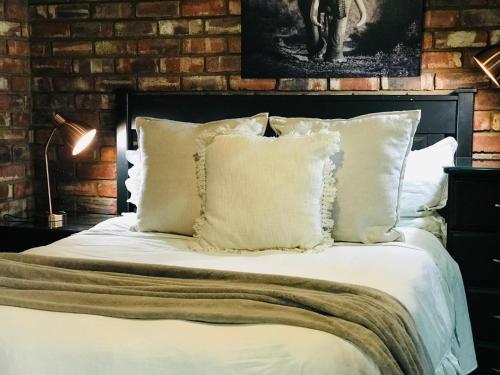 Schlafzimmer mit einem Bett mit weißer Bettwäsche und Kissen in der Unterkunft Aloe Klerksdorp in Klerksdorp