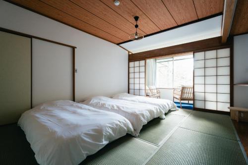 two beds in a room with a window at koti hakone（コティ箱根） in Hakone