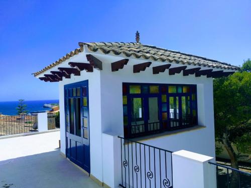 uma pequena casa com portas azuis e vista para o oceano em Can Garba em Porto Cristo