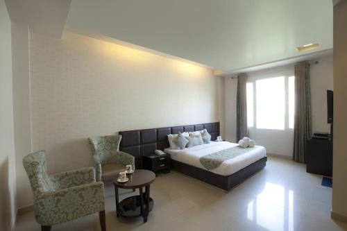 a hotel room with a bed and a chair at Hotel Samrat Heavens Meerut in Meerut