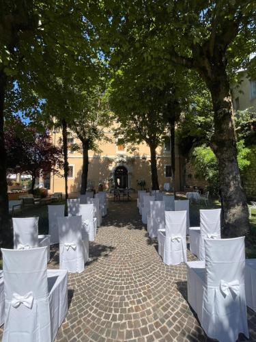 a row of white chairs on a sidewalk with trees at VillaGrancassa Hotel Relais in San Donato Val di Comino