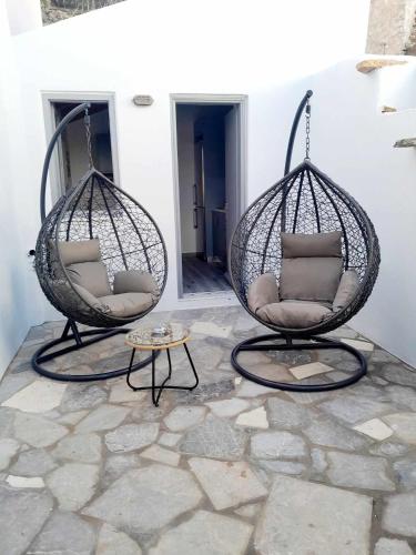 two swing chairs and a table on a patio at "Zeus House" Sevasti Symi Studios in Symi