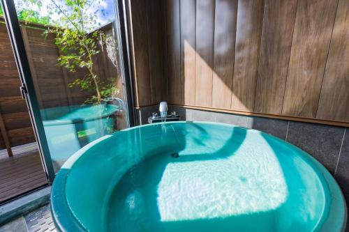 eine blaue Badewanne im Bad mit Fenster in der Unterkunft The Village Yufuin Onsen Glamping in Yufu