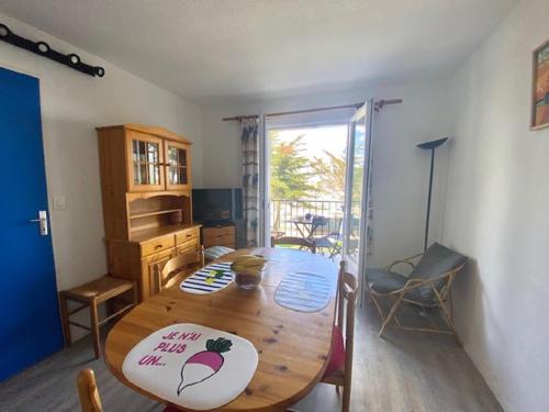 d'une salle à manger avec une table en bois et une porte coulissante en verre. dans l'établissement L'Ancre, à Saint-Gilles-Croix-de-Vie