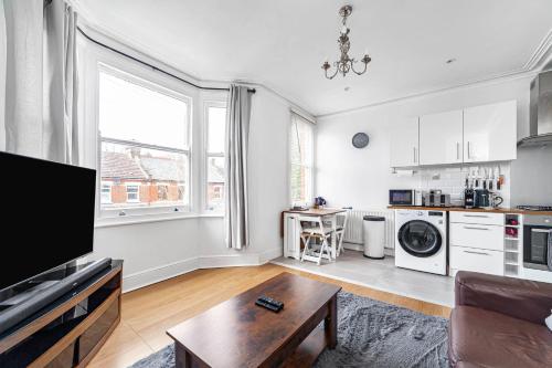 a living room with a table and a kitchen at Bright West Ealing Abode in Hanwell