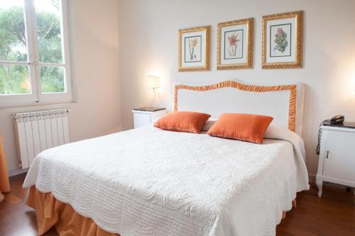 a bedroom with a white bed with two orange pillows at Villa Liberty al mare in Marina di Massa