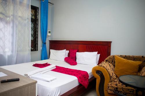 a bedroom with a bed with red pillows and a chair at Magdon Executive Lodge in Dar es Salaam