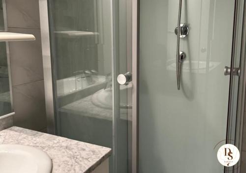 La salle de bains est pourvue d'un lavabo et d'une porte de douche en verre. dans l'établissement Appartement de charme proche stade Vélodrome, à Marseille
