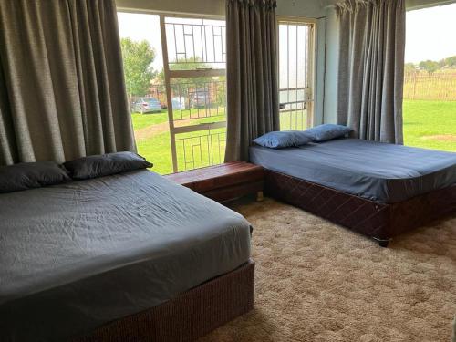 2 camas en una habitación con ventana en Kharimbi Camp House, en Brakpan