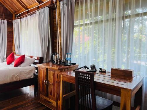 a bedroom with a desk and a bed and a window at บ้านสวนแก้วคำแพง Baan Suan Kaew Khampaeng in Udon Thani
