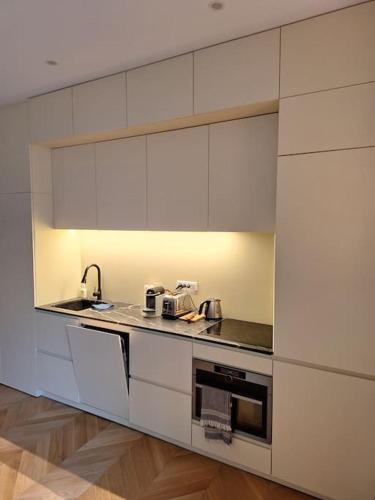 une cuisine avec des armoires blanches et un évier dans l'établissement Appartement 35 m² dans le Marais, à Paris