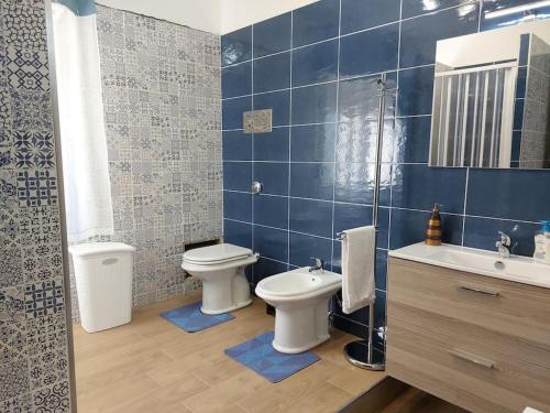 een blauw betegelde badkamer met 2 toiletten en een wastafel bij Appartamento in Villa Lory in Giardinello