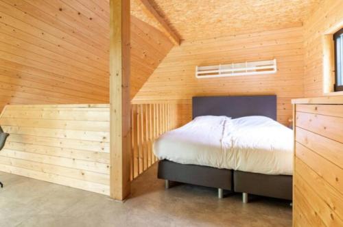 een slaapkamer met een bed in een houten kamer bij Vakantiepark de Eikenhof in Paasloo
