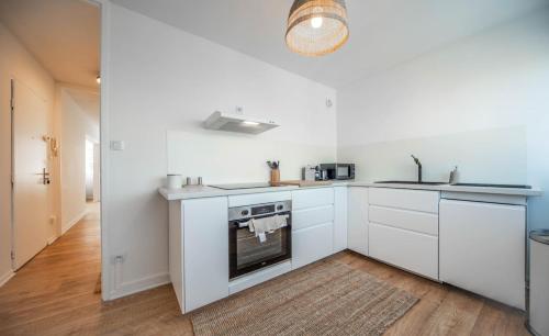 une cuisine avec des armoires blanches et une cuisinière dans l'établissement Le Balinais - Appartement à Chalon-sur-Saône, à Chalon-sur-Saône