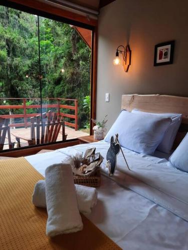 a bedroom with a white bed and a large window at Chalé Mury in Nova Friburgo