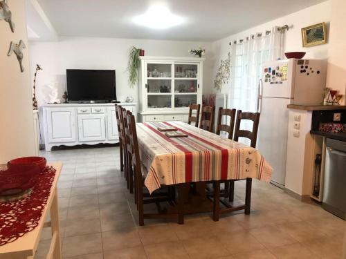 une cuisine avec une table avec des chaises et un réfrigérateur dans l'établissement Maison accueillante en Normandie, à Montivilliers