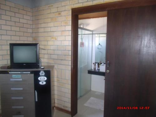 a room with a television on a dresser and a door at Residencial Campo Dunna in Praia do Rosa