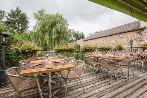 a patio with wooden tables and chairs on a deck at Logis SPA Hotel Restaurant De La Poste in Tence