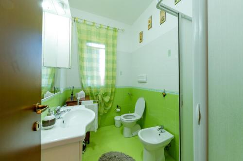 zieloną łazienkę z umywalką i toaletą. w obiekcie Villa Elena w mieście Campofelice di Roccella